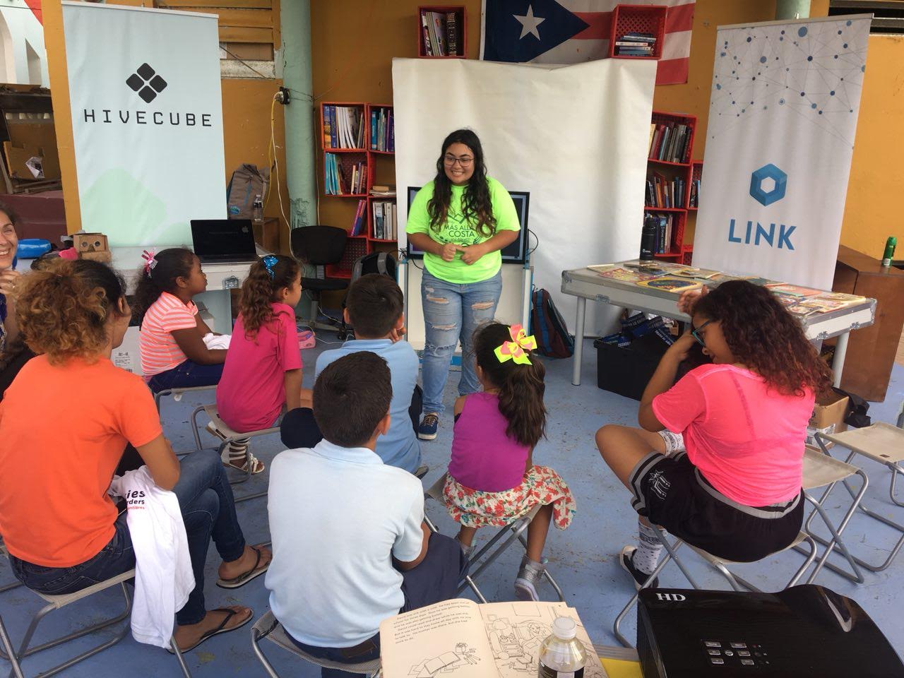 A young woman presents to a group of youth who circle her.