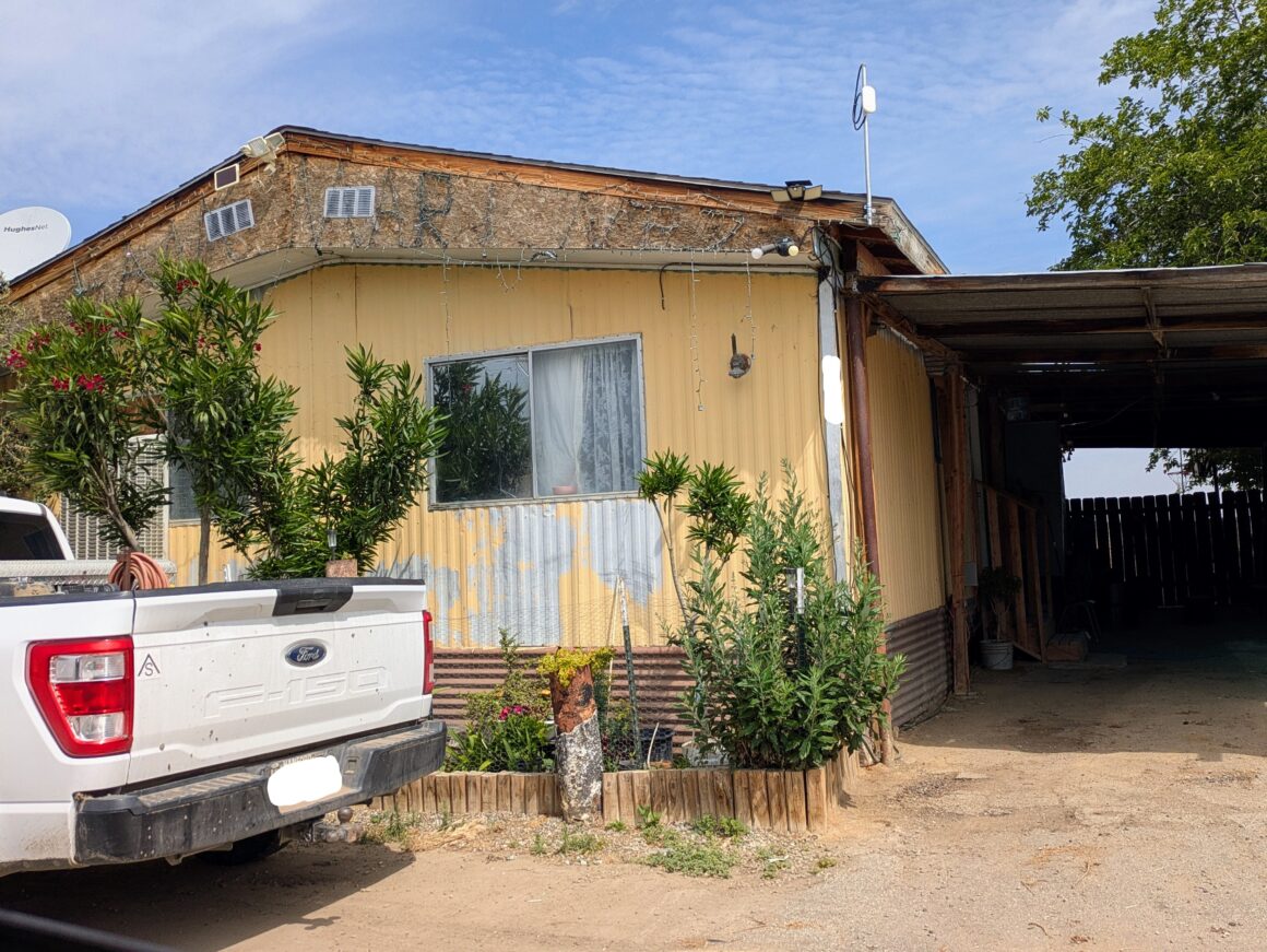 Yellow mobile home, with white pickup truck outside.